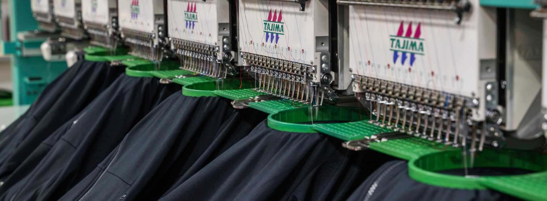 black shirts getting embroidered by a line of embroidery machines