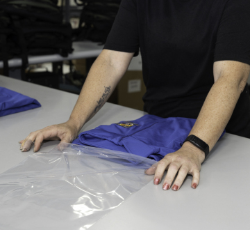 a person placing a a blue shirt in a clear bag