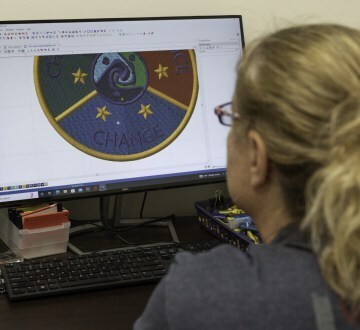a woman looking at a computer with an embroidery design on screen