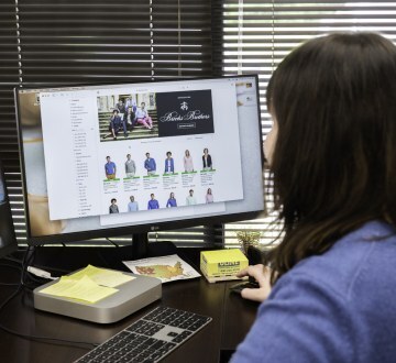a woman looking at a computer screen displaying different clothing options