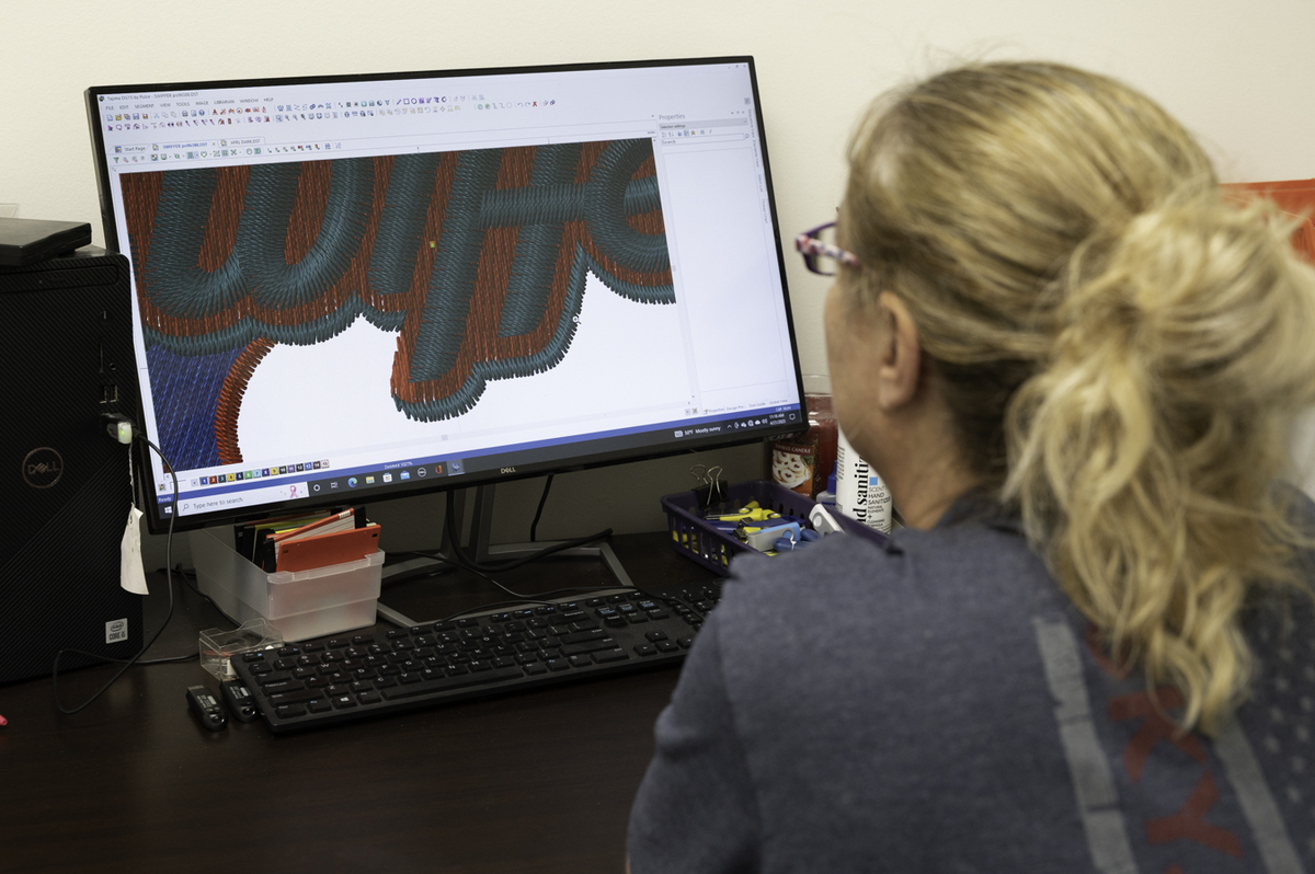 a woman observing an embroidery design on a computer screen